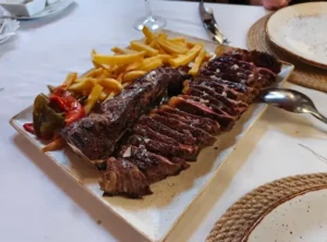 Plato de carne a la brasa con patatas y pimientos servido en un restaurante en Pobla de Farnals